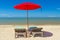 Red parasol with deckchair on tropical beach