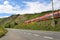 A red passenger train driving alongside an empty motorway next to the hills of a vineyard in Germany.