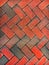 Red paving slabs neatly laid with a herringbone pattern. Sidewalk texture. Red stone background