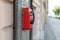 Red pay phone hanging on the granite wall of the old house, against the backdrop of the urban landscape Sunny summer day. Close up