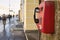 Red pay phone hanging on the granite wall of the old house, on t