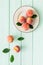Red peaches pattern with plate and leaves on green wooden table top-down