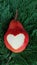 Red pear with a heart shape on green thuja twig, christmas decoration