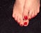 Red pedicure. Women`s legs on a black background. Sock