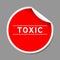 Red peel sticker label with word toxic on gray background