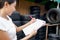 Red pen, paper and clipboard in owner of the auto parts store hand. Several car tires are lined up in a tire shop