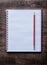 Red pencil and checked notepad on pine wooden