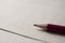 Red pencil lying on blank piece of paper