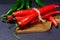 Red pepper and green, on dark wooden board, selective focus. Organic food concept