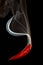 Red pepper pouring smoke on black background