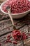 Red peppercorn in bowl and spoon on oak table