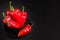 Red peppers in plate on black background with copy space - closeup photo of whole fresh ripe sweet vegetables in modern dark mood