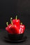 Red peppers in plate on black background with copy space - closeup photo of whole fresh ripe sweet vegetables in modern dark mood