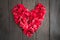 Red petal roses shaped like a heart on wood background,