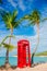 Red phone booth in Dickenson`s bay Antigua. Beautiful landscape with a classic phone booth on the white sandy beach in