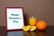 Red photo frame, orange juice and orange slice on wooden table