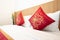 Red pillows in Chinese style put on white bed in the room with wooden on the headboard