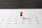 Red pin on calendar on black table background, planning for business meeting or travel planning concept