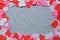 Red, pink, and white heart shaped cut-outs frame on grey fabric background