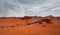 Red planet with arid landscape, rocky hills and mountains, and a giant Mars-like moon at the horizon