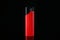 Red plastic cigarette lighter on black background, closeup