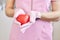 Red plastic heart in female hands, symbol of cardiology department, faceless image of nurse or doctor cardiologist dressed rose