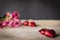 Red plastic hearts placed on a wooden table There is a flower placed on the left back There are red plastic hearts placed backside