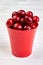 Red plastic pot with fresh cherries.