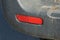 red plastic reflector on a black dirty car bumper