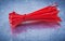 Red plastic self-locking cable ties on metallic background const