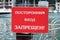 Red plate with inscription Strangers are not allowed to enter, in Russian language. Boat dock