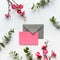 Red plum flowers on twigs, fresh eucalyptus leaves. Blank pink card with grey envelope.