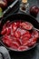 Red plums confiture, jam or fruit sauce in black frying pan.