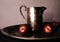 Red Plums on a Tarnished Silver Tray Beside a Tarnished Silver Pitcher