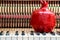 Red pomegranate bibelot on the close up image of grand piano keys and interior background