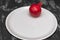 Red pomegranate on big white plate on black and white wooden background. Garnet is a symbol of Judaism.