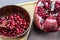 Red pomegranate fruit seeds in a wooden bowl. Pomegranate seeds on a wooden spoon in a bowl. Whole ripe pomegranate open on a