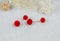 Red pompon earrings in the shape of two fluffy balls.Earrings are next to rattan products, flower specimens and other ornaments