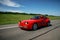 Red Porsche 944 moves along road.