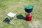 Red portable gas-stove with cauldron on it near chair on green grass. Coocking outside on camping or fishing