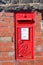 Red postbox mounted in a brick wall