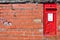 Red postbox mounted in a brick wall
