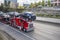 Red powerful big rig car hauler semi truck with loaded modular semi trailer driving on the highway road at the city limit going to
