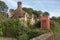 Red public telephone box in garden of Old idilic country brick cottage in chocolate box touristic setting