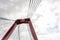 Red pylon and cables of Willemsbrug bridge against cloudy sky