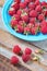 Red raspberry in blue green dish on old vintage wooden table.