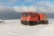 Red ratrak snowcat in winter mountains. A red snow tucker covered with snow.