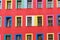 Red rendered facade of an aparemtent building. Each window is pa