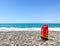 Red rescue float on rocky beach with sea panorama and no lifeguard