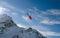 Red rescue helicopter flying over the view of the snowy rocks in Alpine ski resort